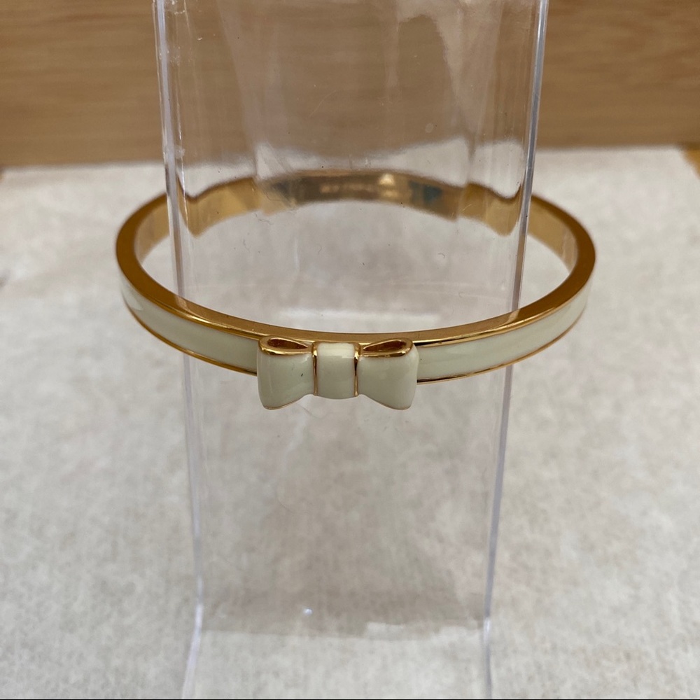 Kate Spade white enamel take a bow goldstone bangle bracelet.